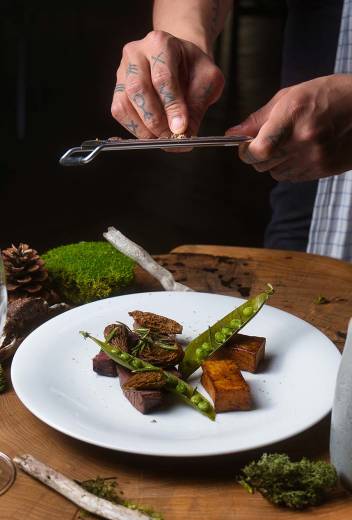 A chef puts finishing touches to a caribou dish served with Labrador tea