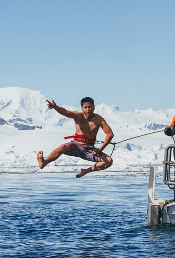 A guest jumps off the gangway (with a safety harness) into Antarctic waters during the Polar Plunge.
