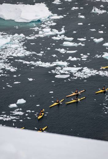 Passengers kayaking in icy landscape