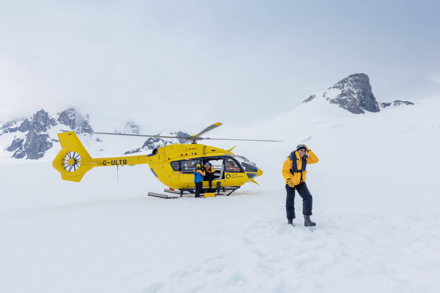 Passengers disembark from a Quark Expeditions Helicopter onto snow covered land