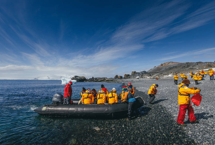 Expedition Guides help guests get out of their zodiac boats on a rocky beach at Half Moon Island.