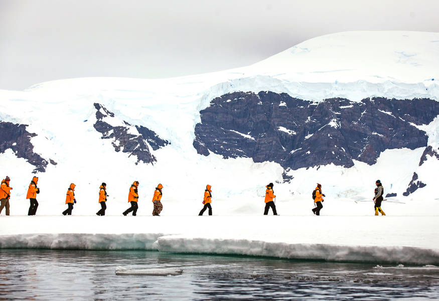 Guests walk in a single file as they explore their surroundings during a sea ice "landing".