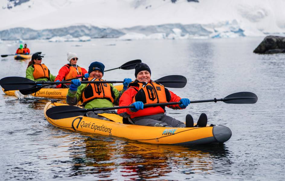 Two guests in dry suits paddle through Antarctic waters onboard our sit-on-top inflatable kayaks.