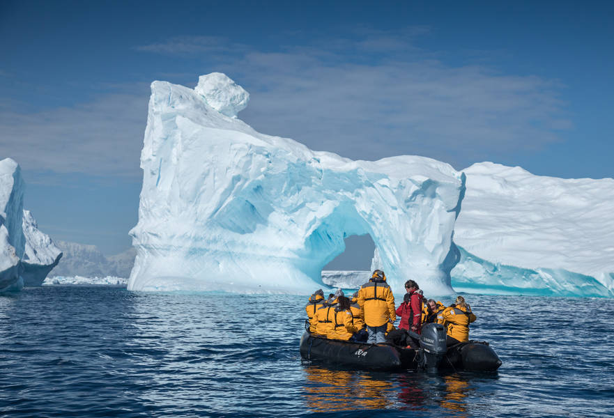 Eleven guests and an Expedition Guide witness a massive iceberg as they stop at a safe distance to capture photographs