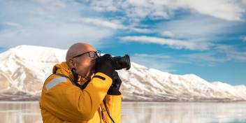Person wearing a yellow parka aims their camera towards the horizon to capture a photograph