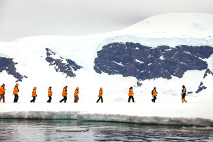 Guests walk in a single file as they explore their surroundings during a sea ice "landing".