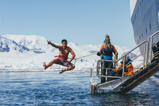 A guest jumps off the gangway (with a safety harness) into Antarctic waters during the Polar Plunge.
