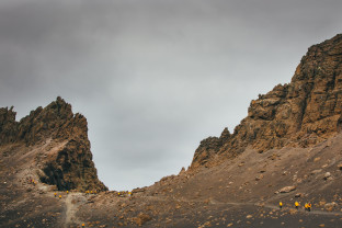 Guests in yellow parkas follow other guests up a hill at Deception Island, Antarctica.