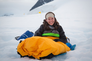 One of our guests smiles for a photo in theie bivvy bag as they wake up after overnight camping in Antarctica.