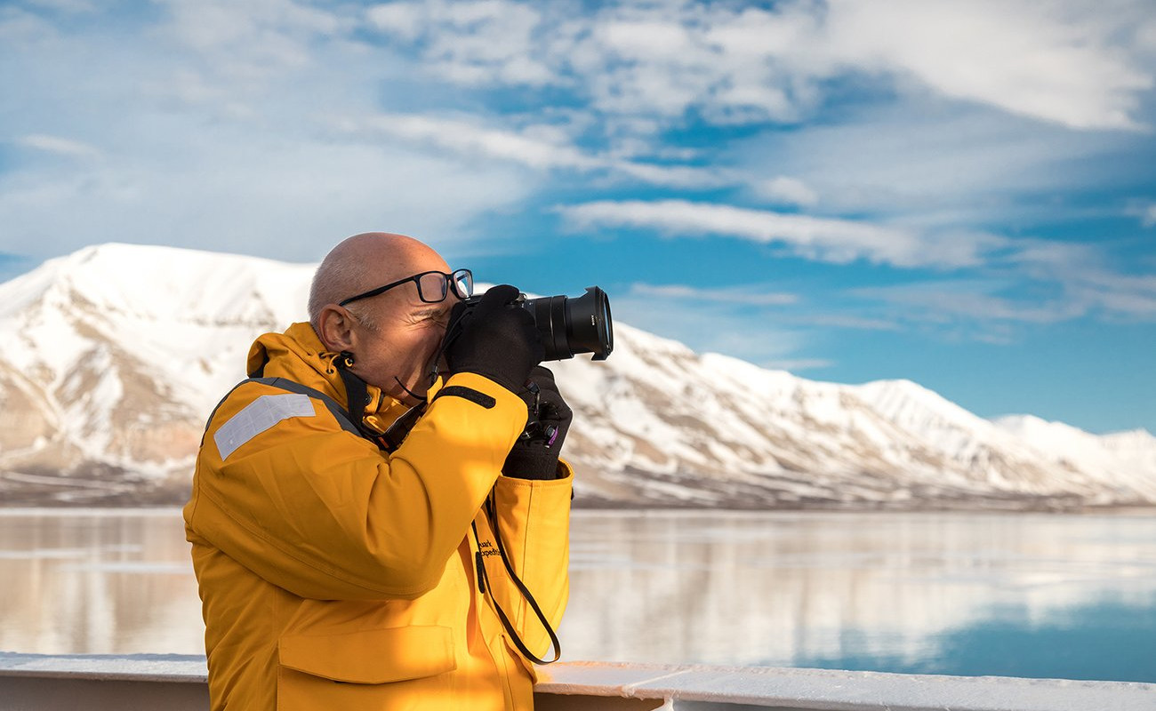 Person wearing a yellow parka aims their camera towards the horizon to capture a photograph