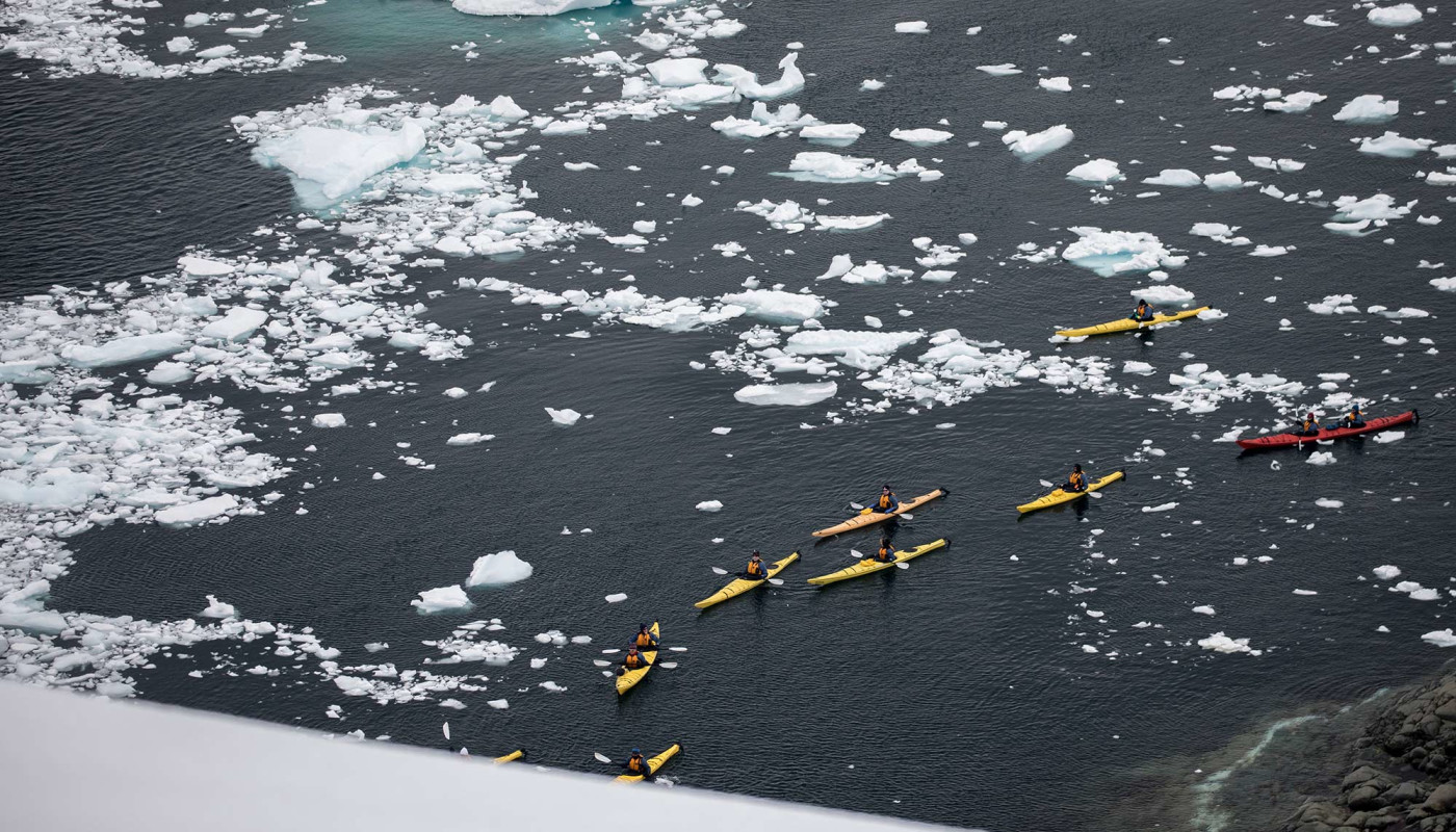 Passengers kayaking in icy landscape